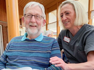 Ein älterer Herr wird von einer Mitarbeiterin betreut